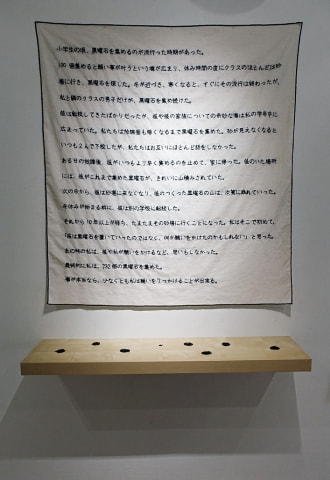 牛島光太郎の作品『意図的な偶然』。日常生活で実際に拾ったモノや、思い入れのあるモノと文字を刺繍した布で構成する作品。