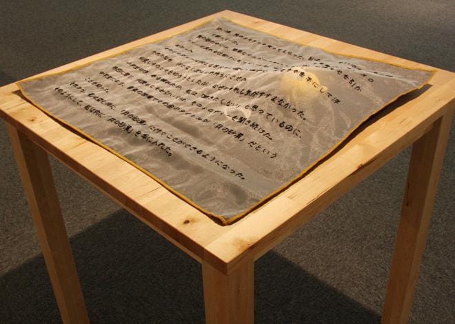 牛島光太郎の作品『意図的な偶然』。日常生活で実際に拾ったモノや、思い入れのあるモノと文字を刺繍した布で構成する作品。