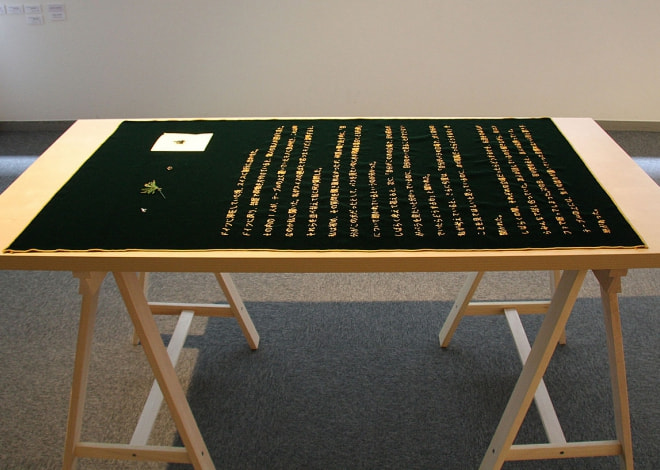 牛島光太郎の作品『意図的な偶然』。日常生活で実際に拾ったモノや、思い入れのあるモノと文字を刺繍した布で構成する作品。