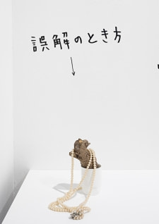 牛島光太郎の作品『組み合わせの方法』。日用品を組み合わせたモノと壁に油性ペンで言葉（文字）を書いた作品。
