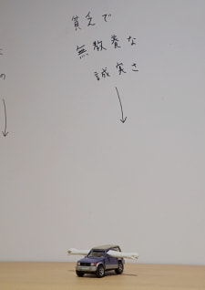 牛島光太郎の作品『組み合わせの方法』。日用品を組み合わせたモノと壁に油性ペンで言葉（文字）を書いた作品。