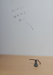 牛島光太郎の作品『組み合わせの方法』。日用品を組み合わせたモノと壁に油性ペンで言葉（文字）を書いた作品。