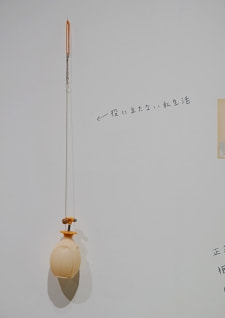 牛島光太郎の作品『組み合わせの方法』。日用品を組み合わせたモノと壁に油性ペンで言葉（文字）を書いた作品。