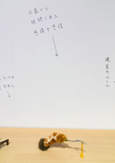 牛島光太郎の作品『組み合わせの方法』。日用品を組み合わせたモノと壁に油性ペンで言葉（文字）を書いた作品。