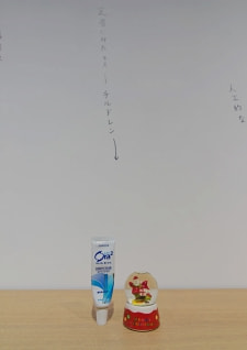 牛島光太郎の作品『組み合わせの方法』。日用品を組み合わせたモノと壁に油性ペンで言葉（文字）を書いた作品。
