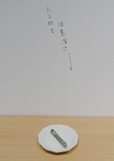 牛島光太郎の作品『組み合わせの方法』。日用品を組み合わせたモノと壁に油性ペンで言葉（文字）を書いた作品。