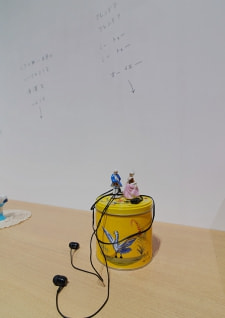 牛島光太郎の作品『組み合わせの方法』。日用品を組み合わせたモノと壁に油性ペンで言葉（文字）を書いた作品。