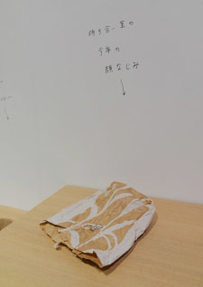 牛島光太郎の作品『組み合わせの方法』。日用品を組み合わせたモノと壁に油性ペンで言葉（文字）を書いた作品。