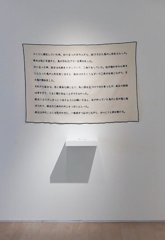 牛島光太郎の作品『意図的な偶然』。日常生活で実際に拾ったモノや、思い入れのあるモノと文字を刺繍した布で構成する作品。